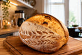 Loaf of bread on a wooden cutting board in a kitchen setting